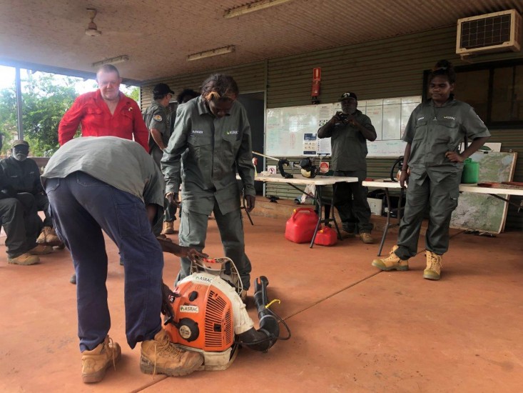 Florence Biridjala tackling a leaf blower with Ian van Munster, Michelle Guyula, Peter Djigirr, Peter Guyula and Erica Ngurruwuthun looking on